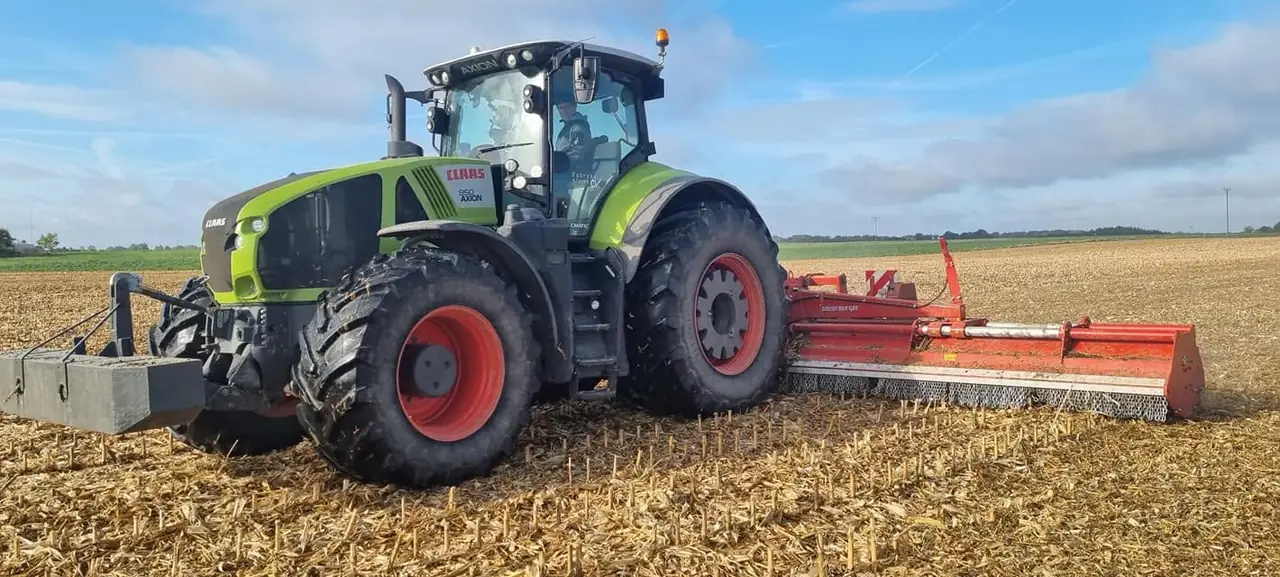 Ciągnik Claas z mulczerem na ściernisku po żniwach.